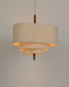 a white lamp hanging from a ceiling with a beige shade on it's side