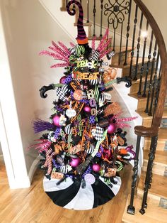 a decorated christmas tree sitting on top of a wooden floor next to a stair case