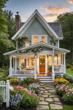 a white house with flowers in the front yard and steps leading up to it's porch