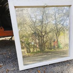 an old window with a reflection of people and trees in the glass on the ground