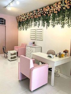 an office with pink chairs and flowers hanging from the wall above it's desk