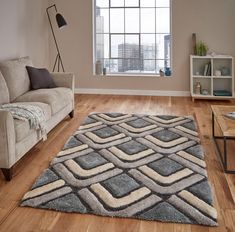 a living room with a couch, coffee table and rug on the wooden flooring