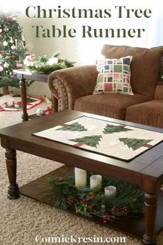 a christmas tree table runner on a coffee table in front of a couch with candles