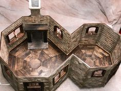 a model of a house made out of wood and stone with two windows on each side