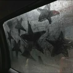 several black stars are seen through the windshield of a car on a rainy day in this image