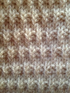 close up view of the texture of a knitted blanket with white and beige colors