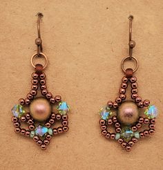 two pairs of earrings with beaded details and beads hanging from hooks on a brown surface