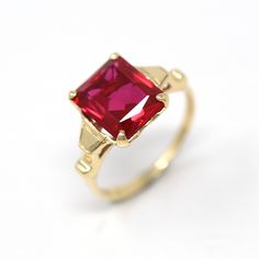 Elegant and classic vintage 10k yellow gold retro 1940s ring featuring a created ruby. The deep red stone is emerald cut, beautifully faceted, weighs approximately 3.60 cts, and is securely prong set. A stunning piece of fine jewelry, featuring July's birthstone color and rose cut accent diamonds! ERA - Circa 1940s, Retro METAL / MATERIAL - 10k yellow gold, created ruby stone (approx. 3.22 ct). (contains essentially the same chemical composition & properties as its natural counterpart, but creat Classic Red Sapphire Promise Ring, Classic Red Birthstone Ring With Prong Setting, Red Classic Birthstone Ring With Prong Setting, Classic Red Ruby Ring With Prong Setting, Classic Birthstone Ring With Prong-set Lab-created Ruby, Classic Red Birthstone Ring With Center Stone, Classic Lab-created Ruby Ring, Classic Red Solitaire Ruby Ring, Classic Yellow Gold Ruby Ring With Lab-created Ruby