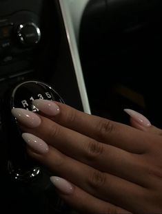 a woman's hand with long, almond - colored nails on the steering wheel