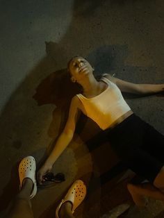 a woman laying on the ground with her feet up next to someone's shoes