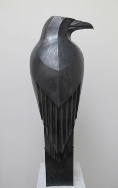 a black bird sculpture sitting on top of a white pedestal