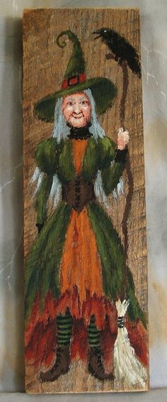 a painting of a witch holding a broom and a cat on a piece of wood