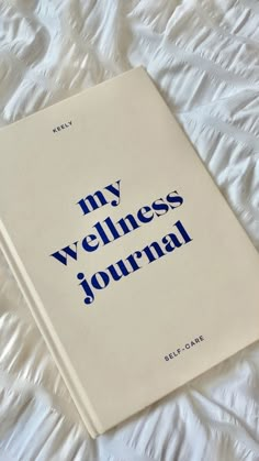 a white book with blue lettering on it sitting on a bed sheet that says, my veinless journal self - care