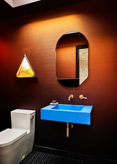 a bathroom with a blue sink and mirror on the wall next to a white toilet