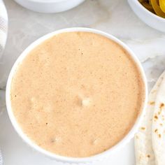 a white bowl filled with soup next to some pita bread