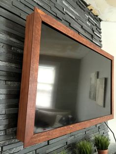 a television mounted to a brick wall next to potted plants