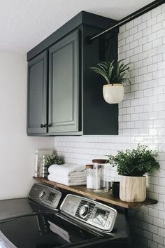 a washer and dryer in a small room with white tiles on the walls