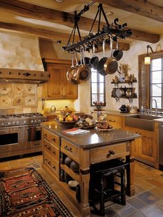 a large kitchen with an island in the middle and pots hanging from it's ceiling