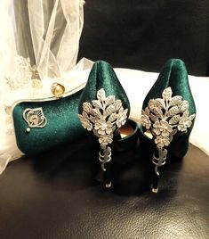 two pairs of green high heeled shoes sitting on top of a black leather table