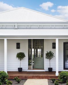 a white house with two potted plants on the front porch