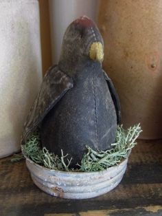 a small bird sitting on top of a white bowl filled with green grass next to two vases