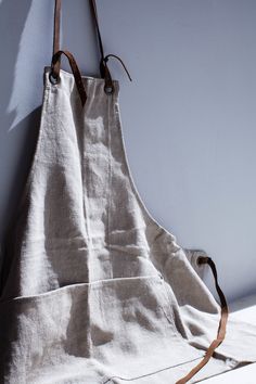 an apron hanging on the wall with a leather strap around it's waist and shoulder