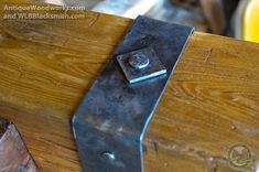 a close up of a piece of metal on top of a wooden table with screws