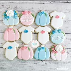 decorated cookies are arranged in rows on a white table with pink, blue and green accents