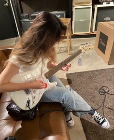 a woman sitting on top of a couch playing an electric guitar