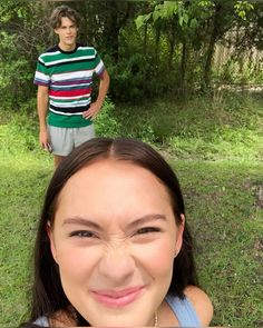 two people are standing in the grass and one person is taking a selfie