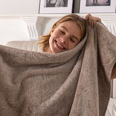 a woman wrapped up in a blanket on top of a bed