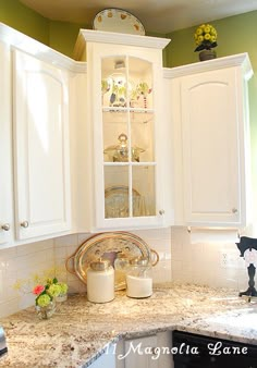 a kitchen with white cabinets and marble counter tops