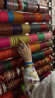 a woman is looking at bracelets on display in a store, with one hand reaching up to the wall