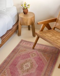 a bedroom with a bed, chair and rug on the floor in front of it