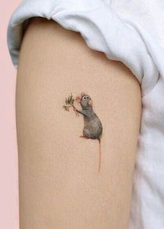 a small rat on the back of a woman's thigh holding a flower in its hand