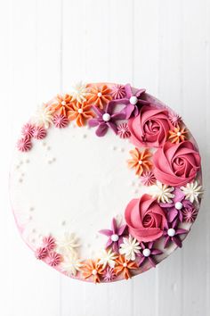 a cake decorated with pink, orange and white flowers