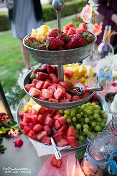 three tiered trays filled with different types of fruit on a buffet table at a party