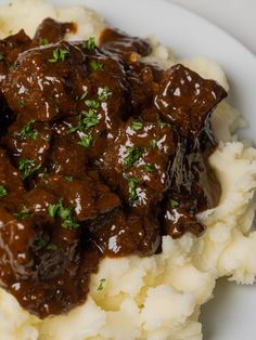 a white plate topped with mashed potatoes covered in gravy