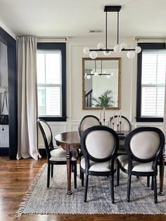 a dining room table with four chairs and a mirror on the wall in front of it