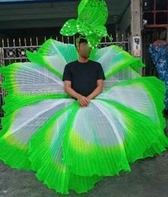 a man wearing a green and white tutu while standing in front of a gate