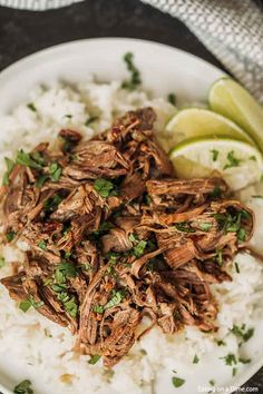 shredded beef and rice on a plate with lime wedges