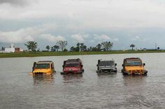 four jeeps are driving through the water