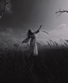 black and white photograph of a woman standing in tall grass with her arms outstretched up