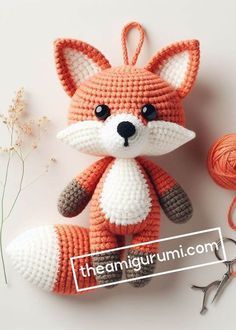 a crocheted fox ornament next to yarn and scissors