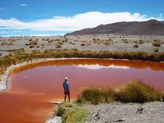 a man standing in front of a red pond