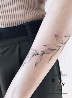 a woman's arm with a leaf tattoo on the left side of her arm