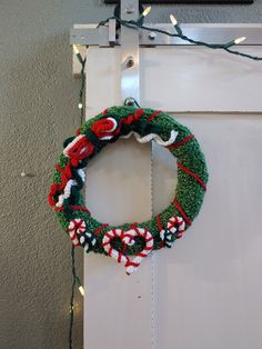 a christmas wreath hanging on the front door with lights around it and an ornament