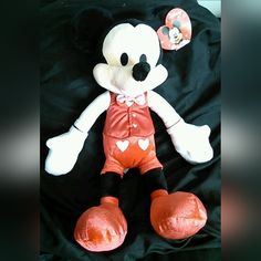 a mickey mouse stuffed animal is laying on a black sheet