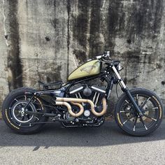 a black and gold motorcycle parked in front of a stone wall with graffiti on it