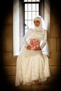 a woman sitting on a window sill holding a bouquet of flowers